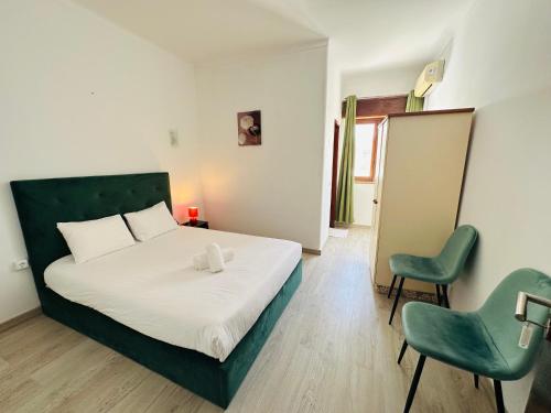 a bedroom with a bed and two green chairs at Residencial Pimenta ,Portimao,Algarve in Portimão