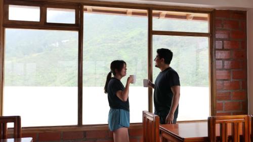 a man and a woman standing in front of a window at Hotel Shannon 360 in Baños