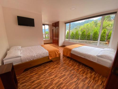 two beds in a room with a large window at Hotel Shannon 360 in Baños