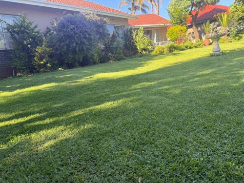 a yard with a green lawn in front of a house at Horizon Bed and Breakfast in Roodepoort