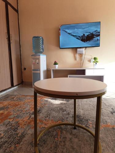 a table in a room with a tv on the wall at Lablu Studio Apartment in Mombasa