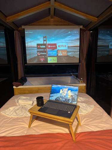 a laptop on a table on a bed with a tv at Ria süit otel bungalov in Rize