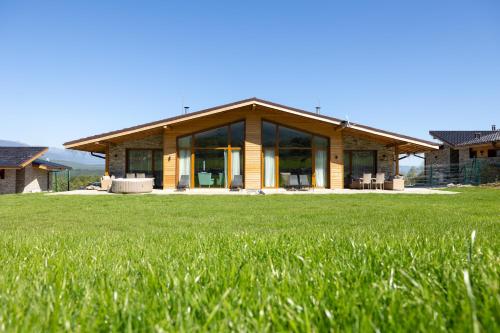 a house with a large green field in front of it at Villa Eliyas with Jacuzzi near the Pirin Golf Resort in Razlog