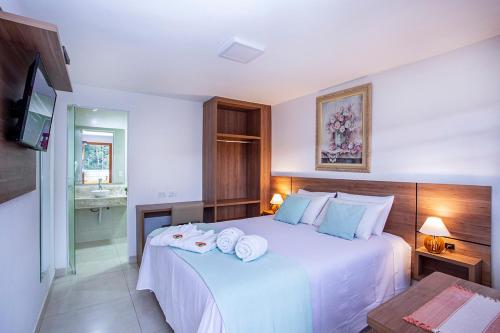 a bedroom with a large white bed with towels on it at Pousada das Videiras boutique in Monte Verde