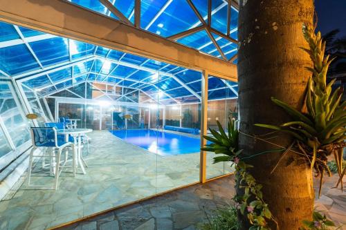 a glass house with a swimming pool with a table and chairs at Pousada das Videiras boutique in Monte Verde