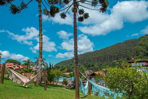 a person swinging on a hammock in a park with palm trees at Pousada das Videiras boutique in Monte Verde