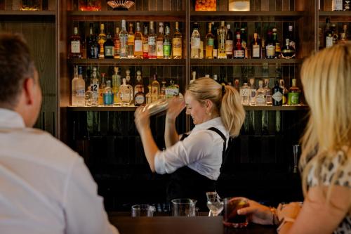 una donna in piedi al bar che prepara un drink di Flockhill a Cass