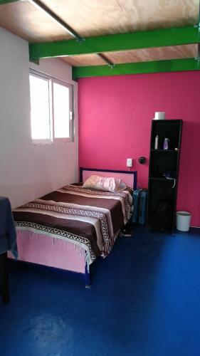 a bedroom with a bed and a pink wall at Posada Doña Mari Aeropuerto in Mexico City