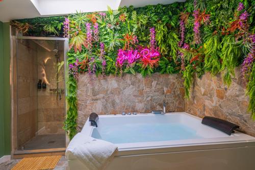 a bathroom with a tub with flowers on the wall at Suite jungle amour détente in La Flèche