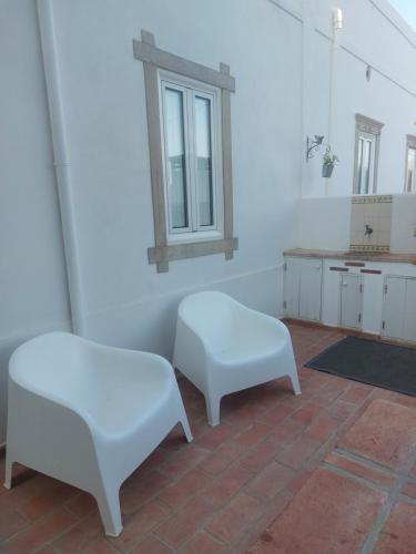 Habitación con 2 sillas blancas y mesa. en Cosy Country House, en Cerro da Cova