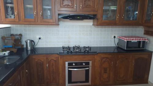 a kitchen with wooden cabinets and a stove and a microwave at Atlas Celestial Park in Nedumbassery