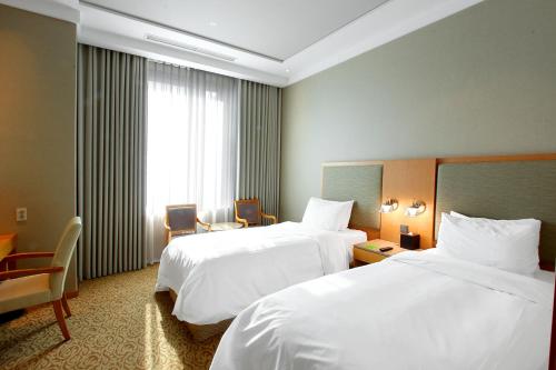 a hotel room with two beds and a window at Daegu Grand Hotel in Daegu