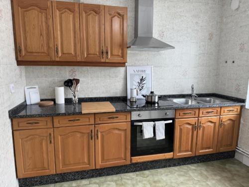 Una cocina con gabinetes de madera y un fregadero. en Apartamento a Un Paso de la Playa de Tapia, en Tapia de Casariego