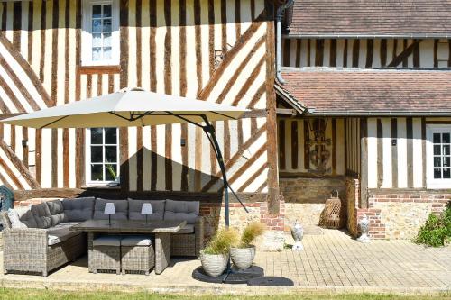 a patio with a table and an umbrella at Au Clos de la Bergerie - campagne, détente & pétanque in Pont-lʼÉvêque
