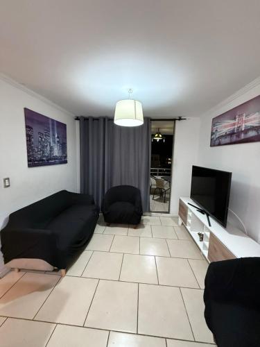 a living room with a couch and a flat screen tv at Departamento Portal del Norte 1 in Arica
