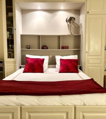 a bedroom with a large bed with red pillows at L'écrin du 12- Studio élégant sur jardin avec parking in Paris