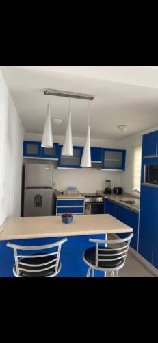 a kitchen with blue cabinets and a counter with two chairs at Casa Nuevo Vallarta in Jarretadera
