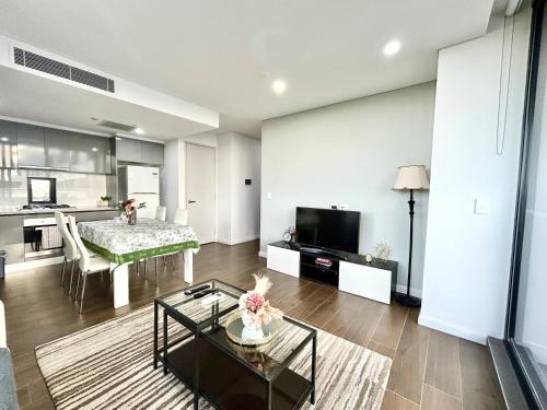 a living room with a table and a kitchen at Sun-filled Apt w Stunning Open Views of Park&City in Sydney