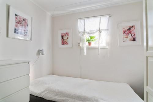 a white bedroom with a bed and a window at Lövnäs Sommarhus in Sörsjön