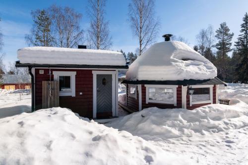 a small house covered in snow next to a pile of snow at Lövnäs Sommarhus in Sörsjön