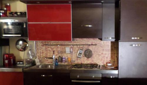 a kitchen with red cabinets and a sink and a stove at Grand Tour Suite Home in Spoleto