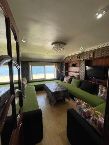 a living room with green couches and a couch at BEACHFRONT VUE SUR MER APPARt in Dar Merah Deriba