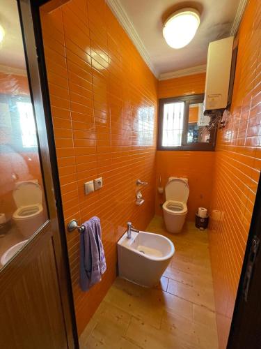 an orange bathroom with two toilets and a sink at BEACHFRONT VUE SUR MER APPARt in Dar Merah Deriba