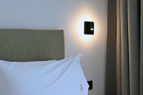a bed with a white pillow and a light on a wall at Agios Nikolaos Villas in Ayios Nikolaos Sithonia