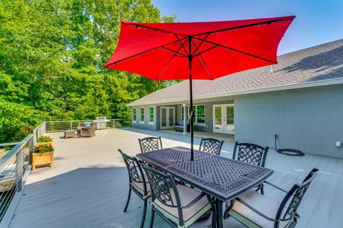 a table with a red umbrella on a deck at Deck and Gas Grill Riverfront Home in Heber Springs in Heber Springs