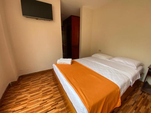 a bedroom with a bed and a flat screen tv at Hotel Shannon 360 in Baños