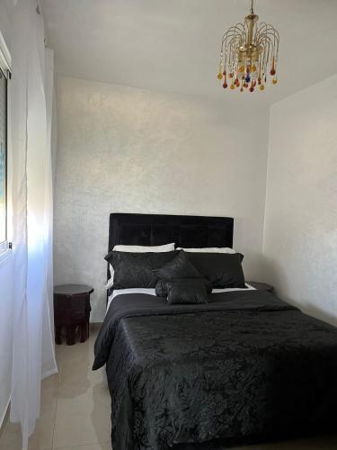 a bedroom with a black bed and a chandelier at Beach Condo - 2 Mins from Ocean in Tangier
