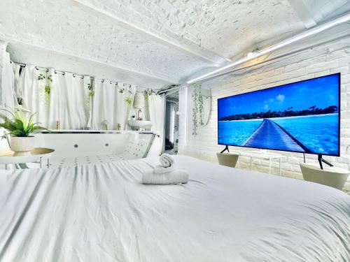 a bedroom with a large bed and a large screen tv at 9 Mykonos , Spa Balnéothérapie - espace aménagé privatif avec Lit Double in Tourcoing