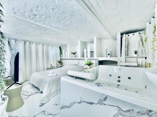 a white bedroom with a tub and a bed at 9 Mykonos , Spa Balnéothérapie - espace aménagé privatif avec Lit Double in Tourcoing