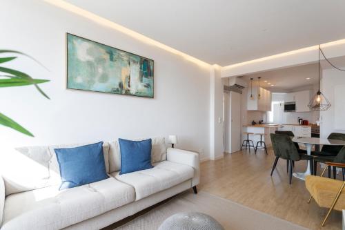 a living room with a white couch with blue pillows at Cozy Apartment for Family and Group of Friends in Linda-a-Velha