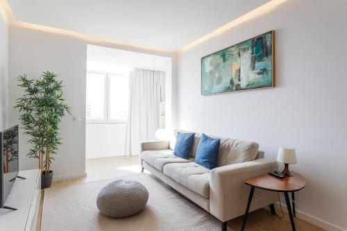 a white living room with a couch and blue pillows at Cozy Apartment for Family and Group of Friends in Linda-a-Velha