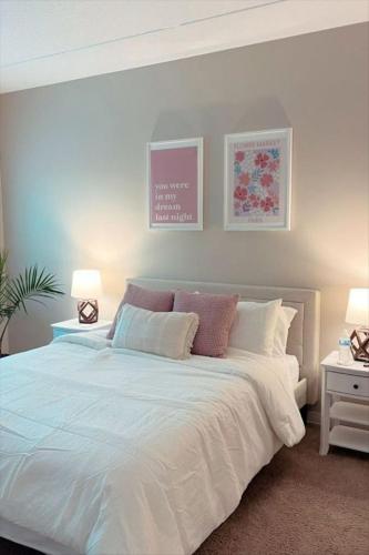 a bedroom with a large white bed with two lamps at Hostel Paradiso in Chaguanas