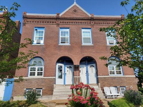 a red brick building with white doors and flowers at The Bleu Guitar Suite in Saint Louis