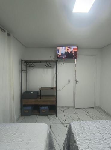 a room with two beds and a tv on the wall at Casa aconchegante no centro da cidade in Itatiba