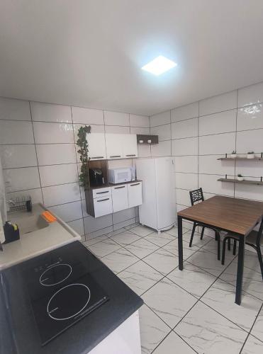 a small kitchen with a table and a refrigerator at Casa aconchegante no centro da cidade in Itatiba