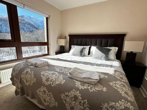 a bedroom with a large bed and a large window at Departamentos Exclusivos Termas de Chillán in Nevados de Chillan