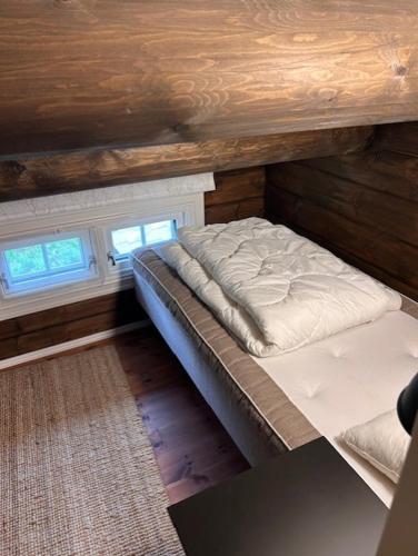 a bed in a room with wooden walls and windows at Sjarmerende tømmerhytte på Bjorli in Bjorli