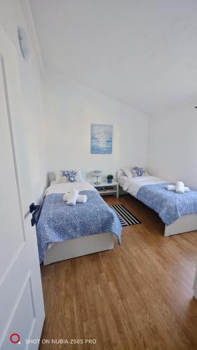 two beds in a white room with wooden floors at Apartman Lunna in Vrsi