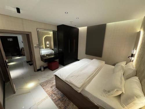 a bedroom with a large white bed and a bathroom at SIXTY THREE HOTEL SUiTES in Riyadh