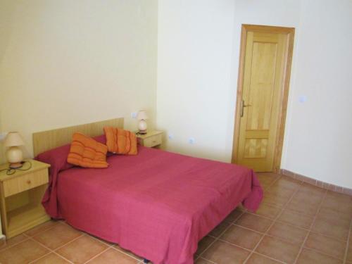 um quarto com uma grande cama rosa com almofadas laranja em Apartamentos Creoli em Ayamonte