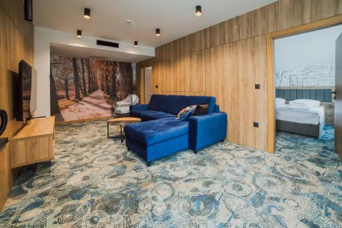 a living room with a blue couch and a bedroom at Hotel Boutique Anoma in Sarajevo