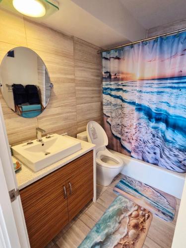 a bathroom with a sink and a toilet and a shower curtain at Ocean & Marina View Suite in Honolulu