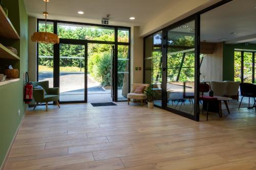 a living room with glass doors and a wooden floor at Hôtel La Cachette de Nina- Madame rêve - Saint-Girons in Saint-Girons