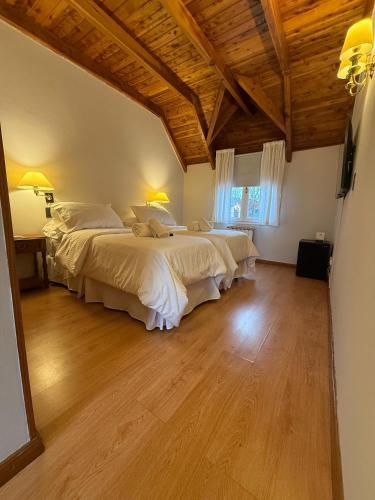 two beds in a large room with wooden ceilings at Hosteria Las Walkirias in San Martín de los Andes