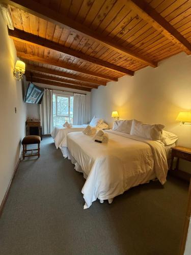 a bedroom with two beds with white sheets at Hosteria Las Walkirias in San Martín de los Andes