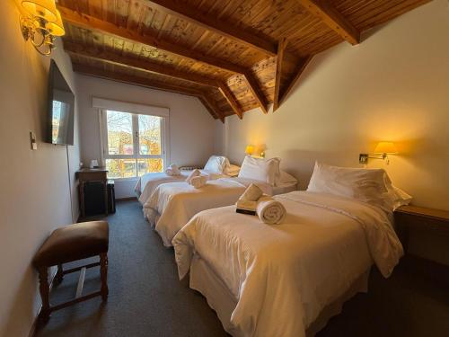 a bedroom with three beds with white sheets and a window at Hosteria Las Walkirias in San Martín de los Andes